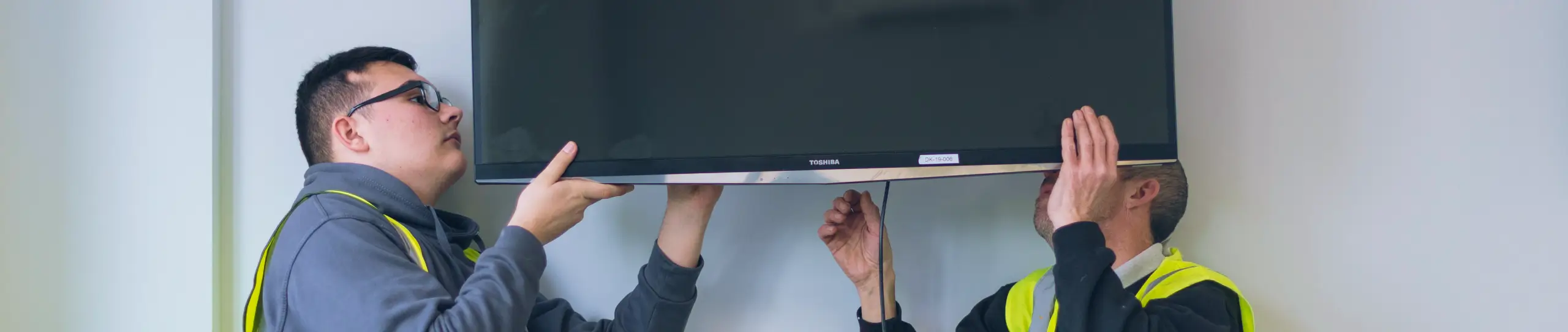 EPS engineers lifting a TV onto a wall